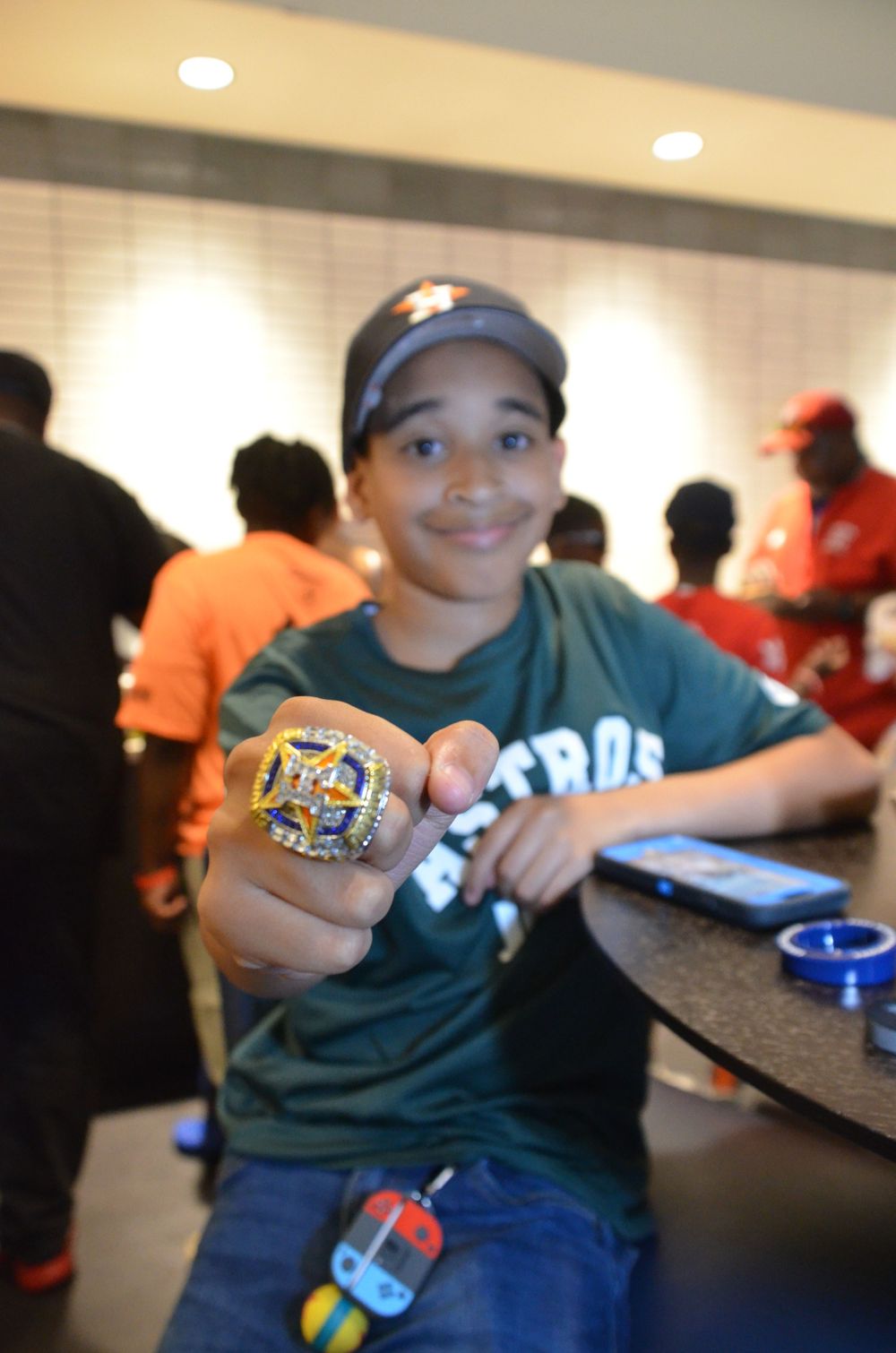 Young baseball fan shows off championship ring at team event.