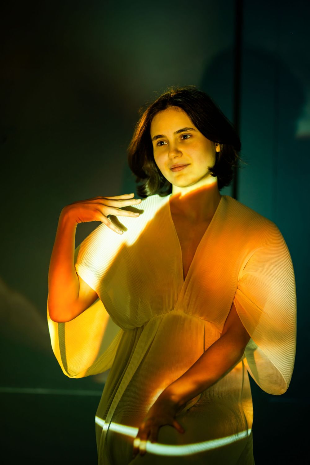 An artistic portrait illuminated by dramatic yellow and orange lighting against a dark background.