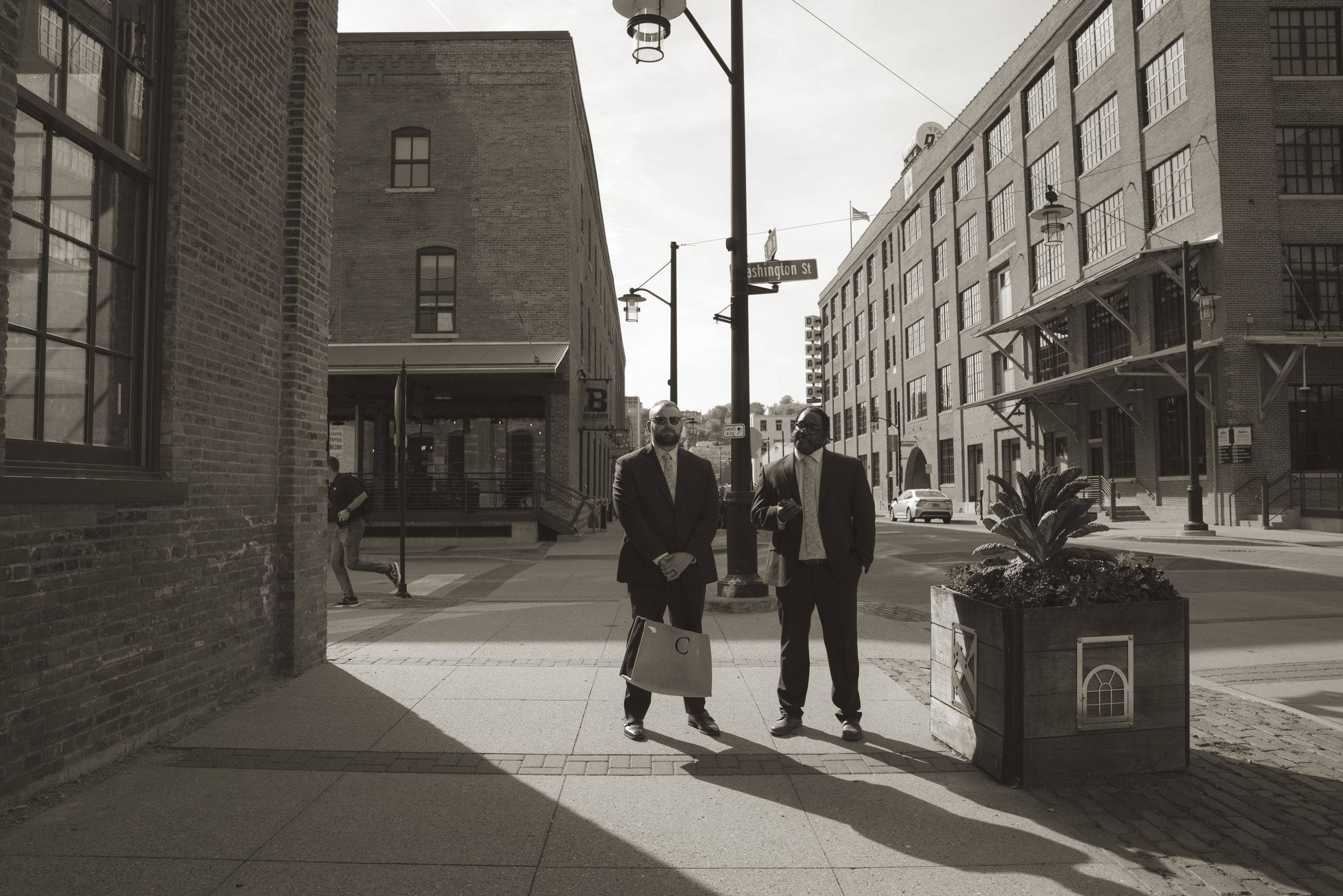 Black and white urban street scene with industrial brick buildings and vintage atmosphere.