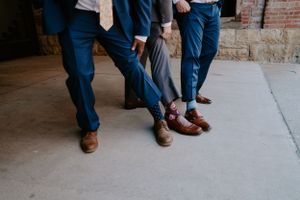 Detail shot of wedding party members' feet walking on concrete sidewalk.