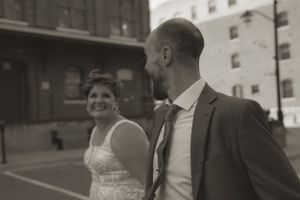 Wedding guests gather and smile in front of an industrial brick building.