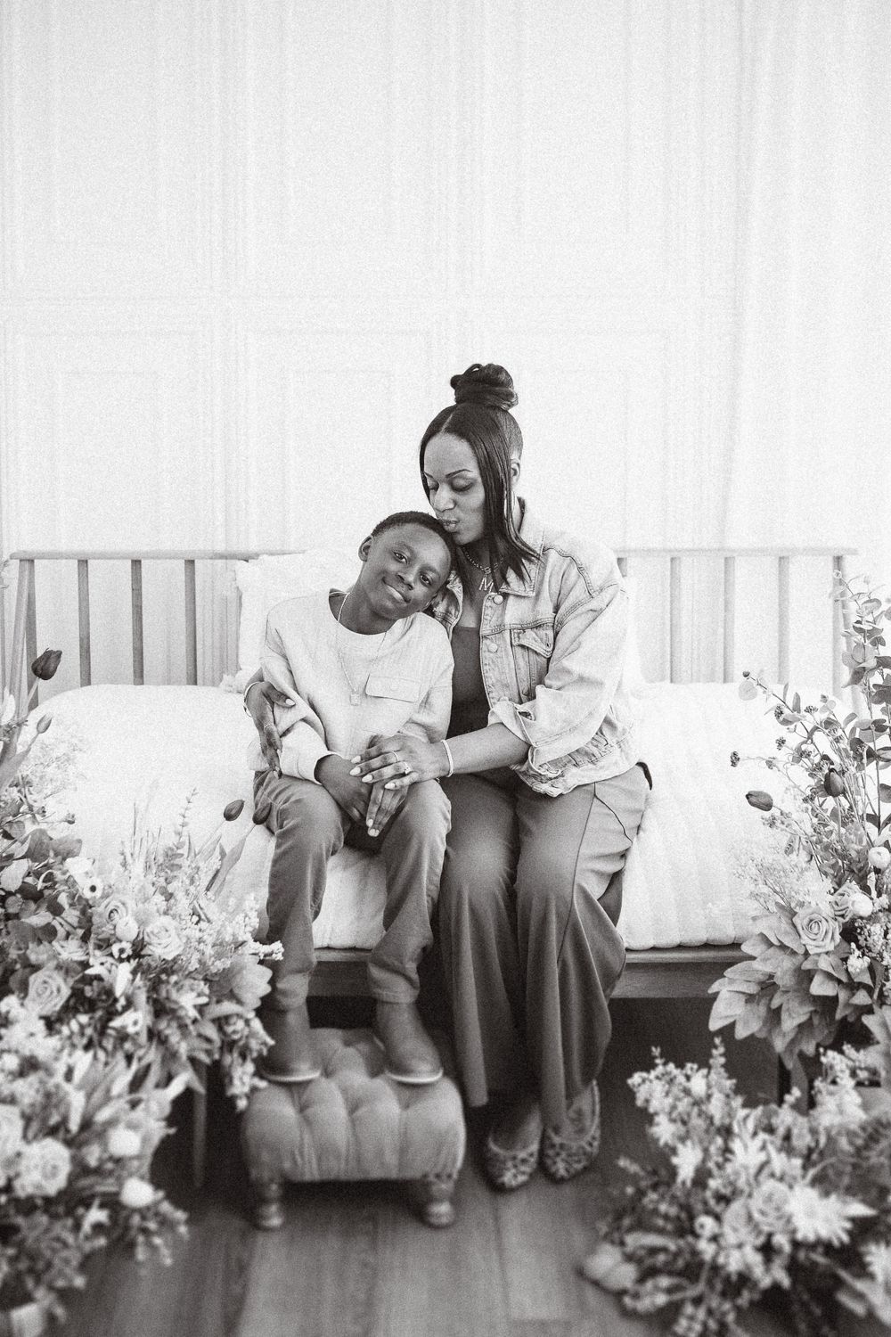 A heartwarming black and white portrait of maternal love as parent and child share an intimate moment among flowers.