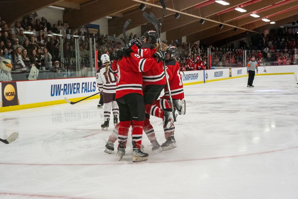 Ice hockey players in red and white jerseys celebrate together on the rink during a game.