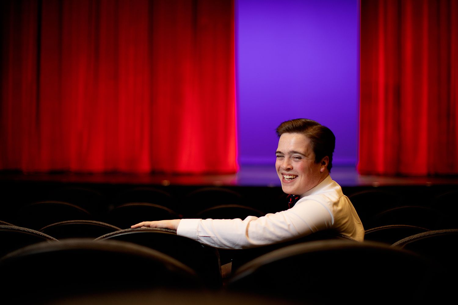 Male teen wearing a white button up in the audience of the Ned McWherter Theater in Jackson, TN. Senior picture by MegMc Photography