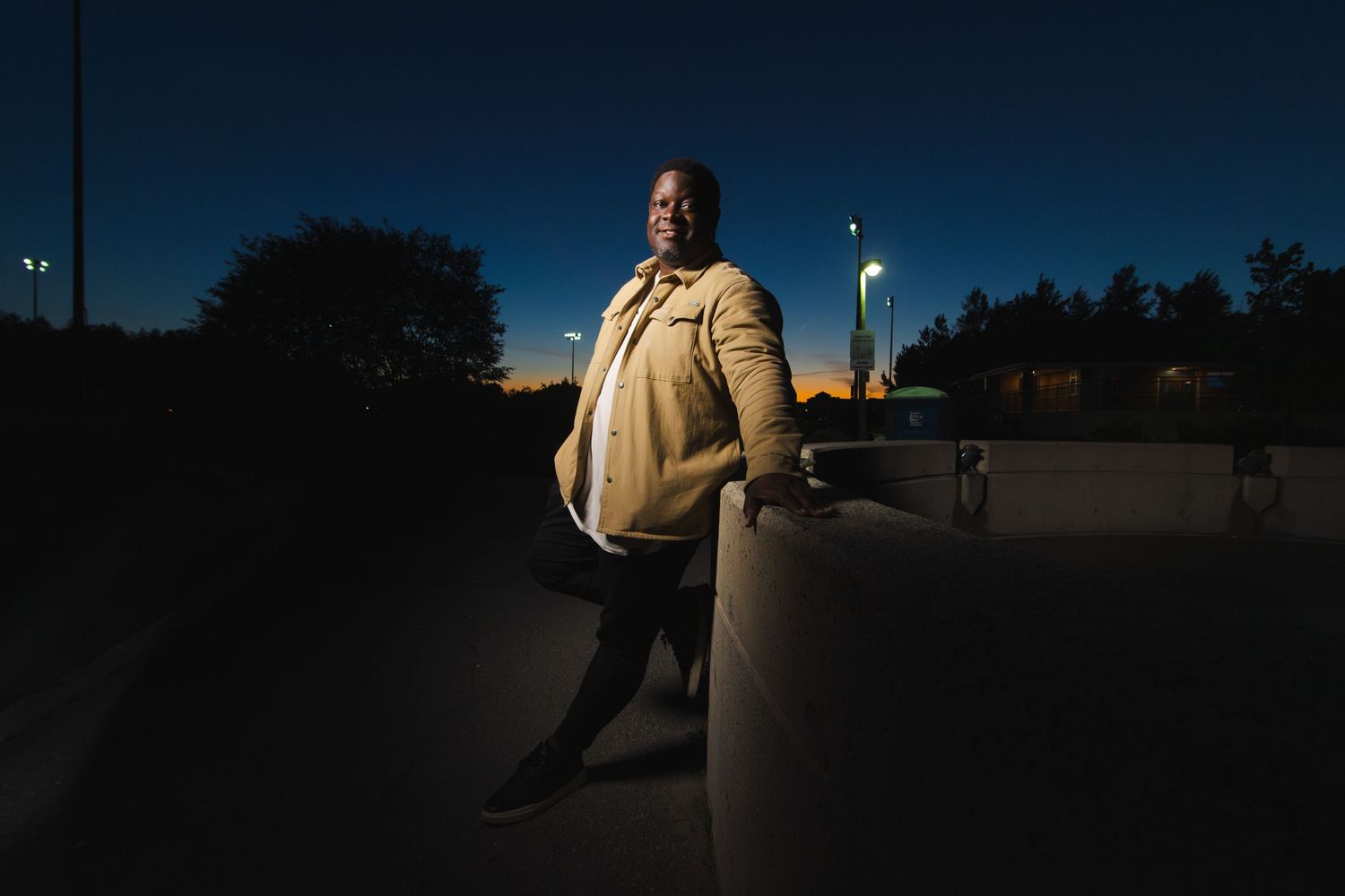 A person stands in dramatic nighttime lighting against an urban backdrop.