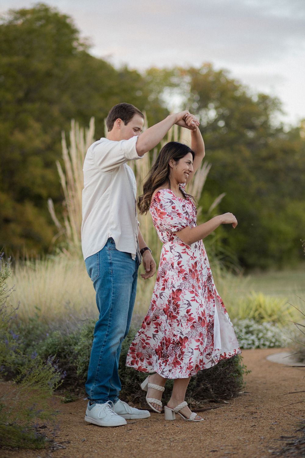 A joyful dancing moment captured on a nature trail with ornamental grasses in the background.