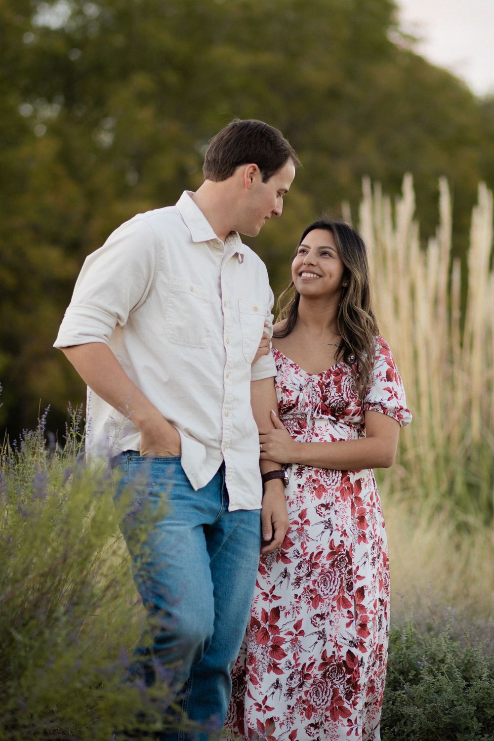 A casual outdoor portrait against decorative grasses shows a couple sharing a lighthearted moment.