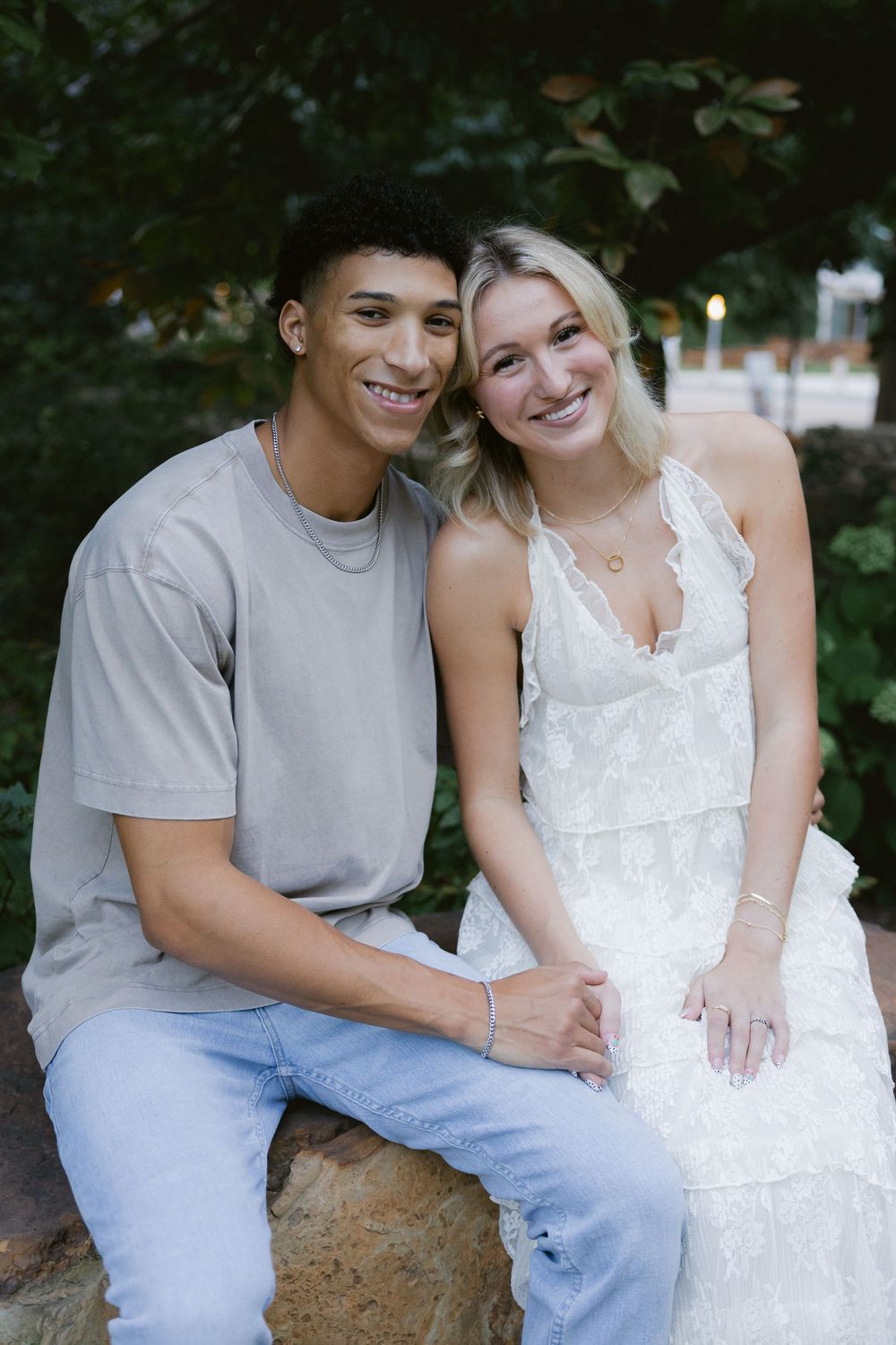A couple sits together outdoors sharing sweet moments in a romantic photoshoot series.