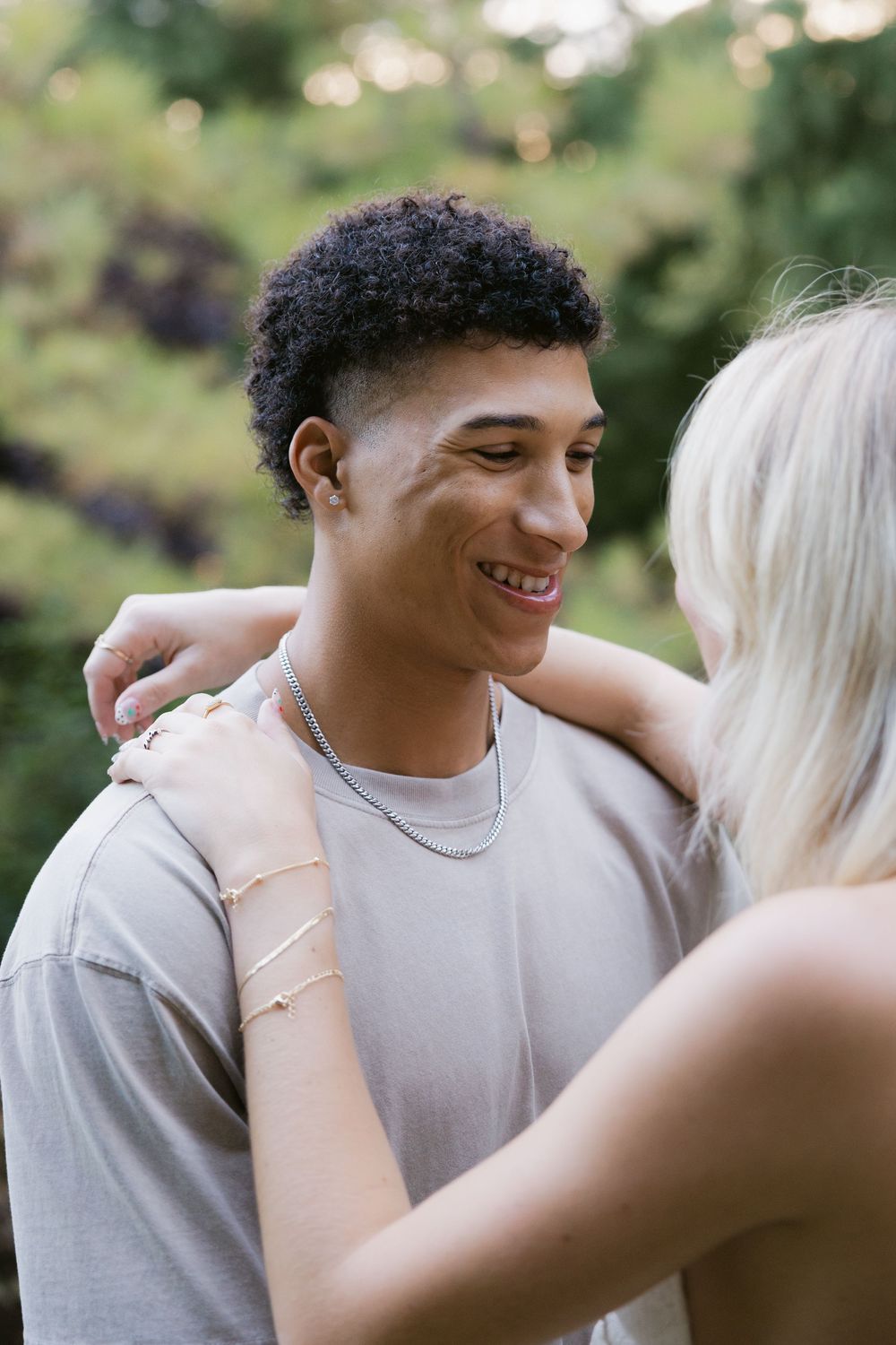 A couple shares intimate moments in a series of candid outdoor photos with natural bokeh lighting.