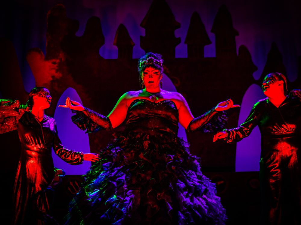 Dramatic silhouette of performers dancing against purple-lit castle battlements backdrop.