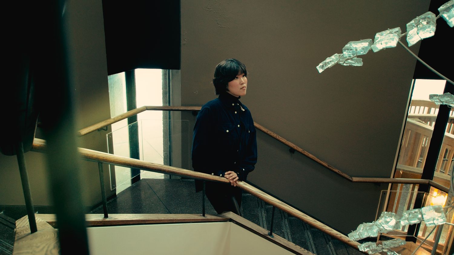 Portrait of person looking up while leaning on stair railing
