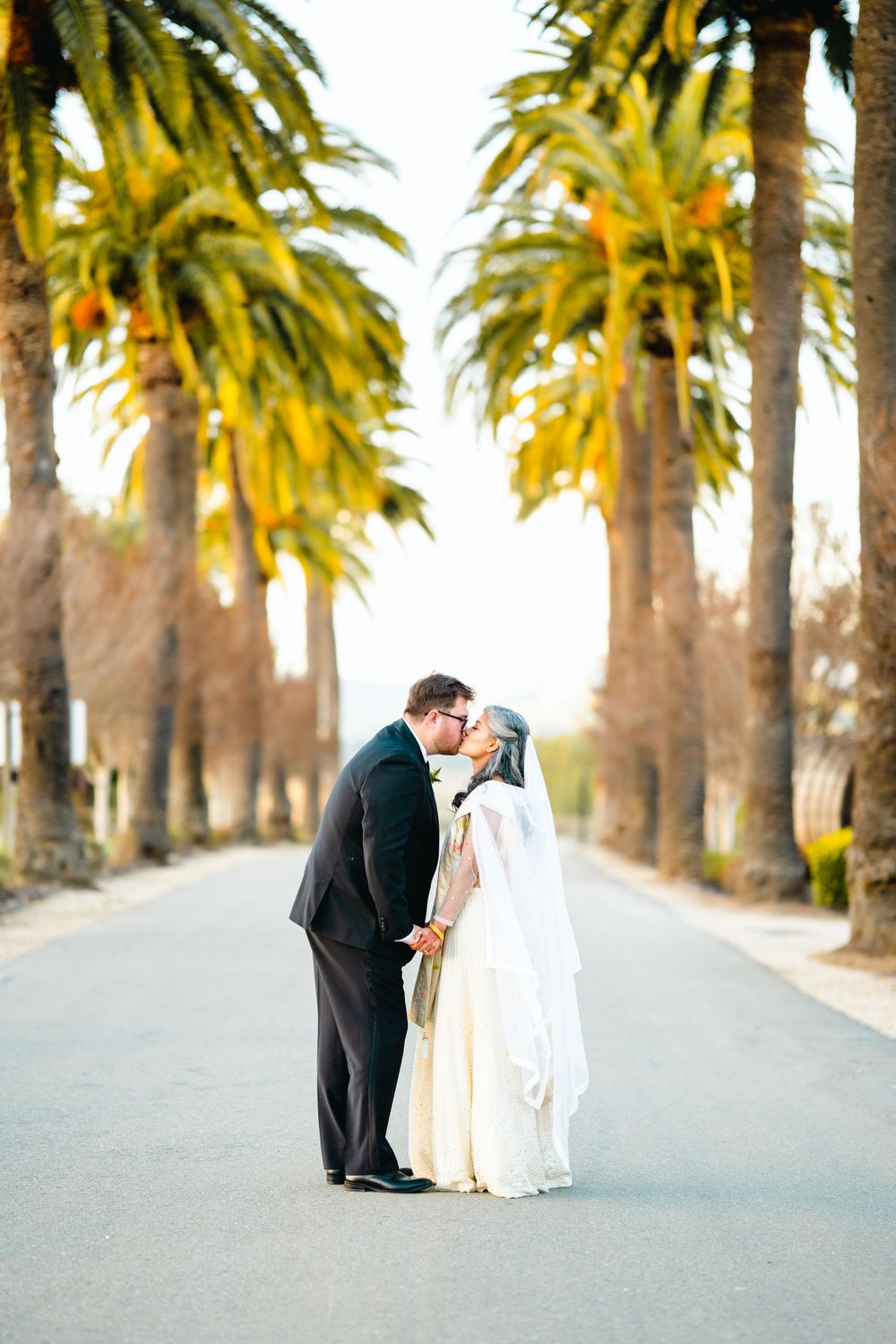 Romantic moment between couple beneath towering palm trees at sunset.