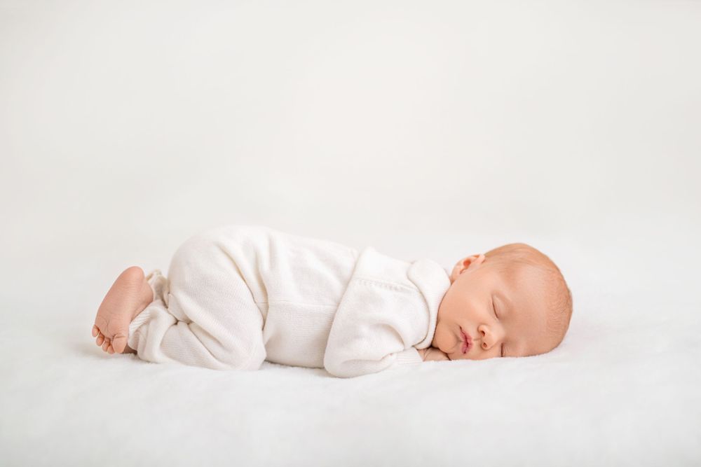 Newborn photography in Winchester VA – baby sleeping on white bed by Beryl Photography