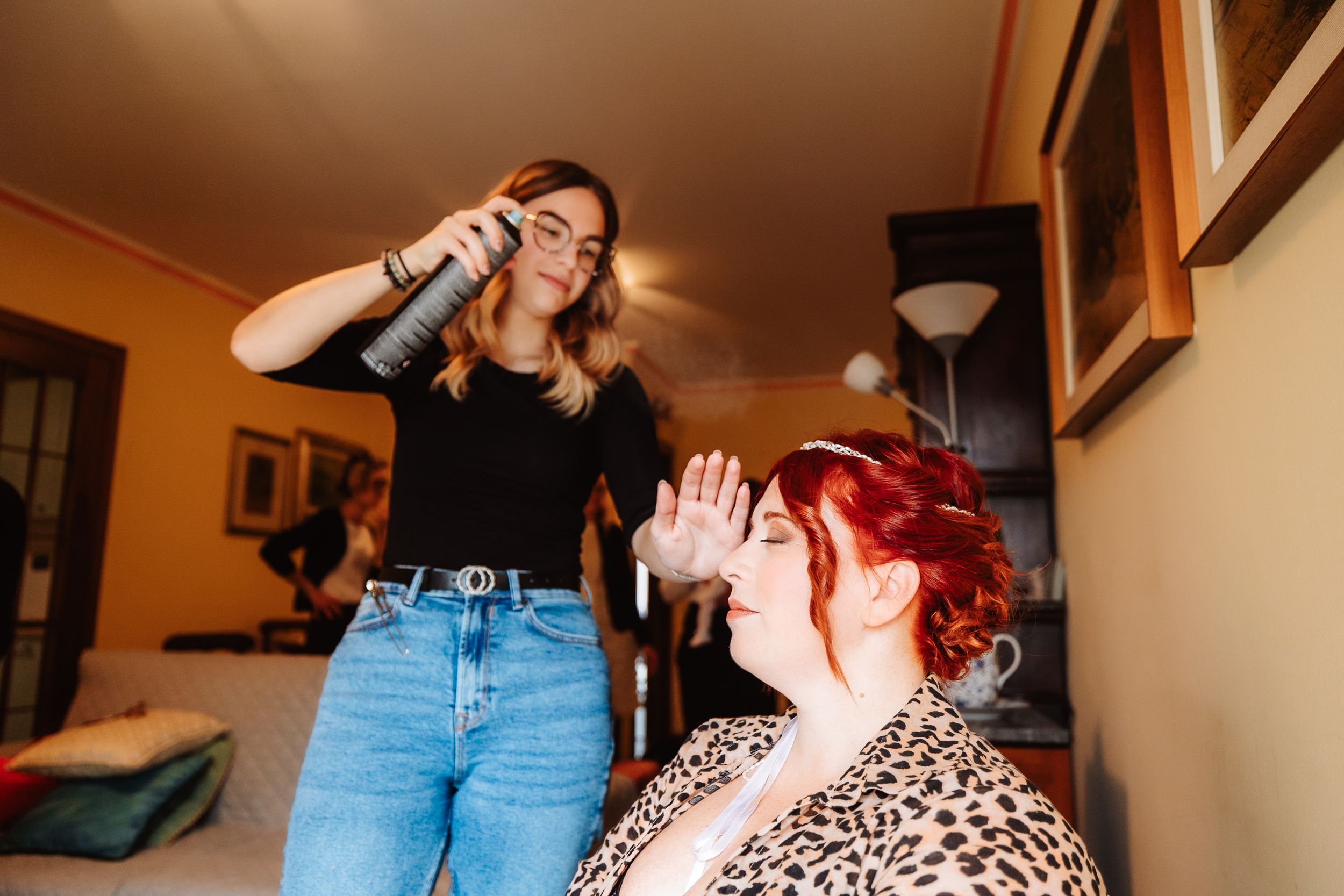 Two friends having fun posing dramatically in a home setting with orange walls and casual attire.