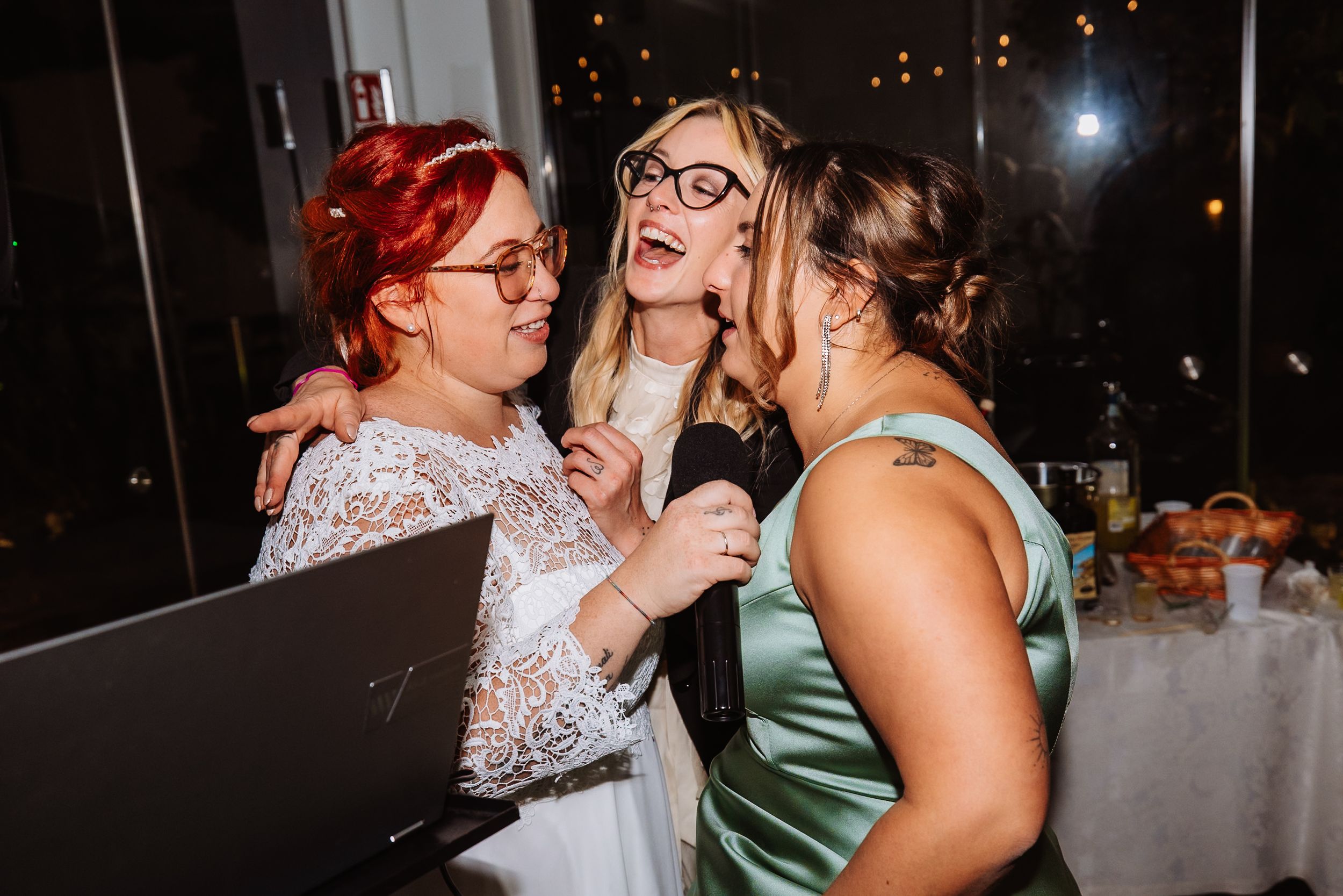 Three excited party guests sharing a fun moment while singing karaoke at a celebratory event.