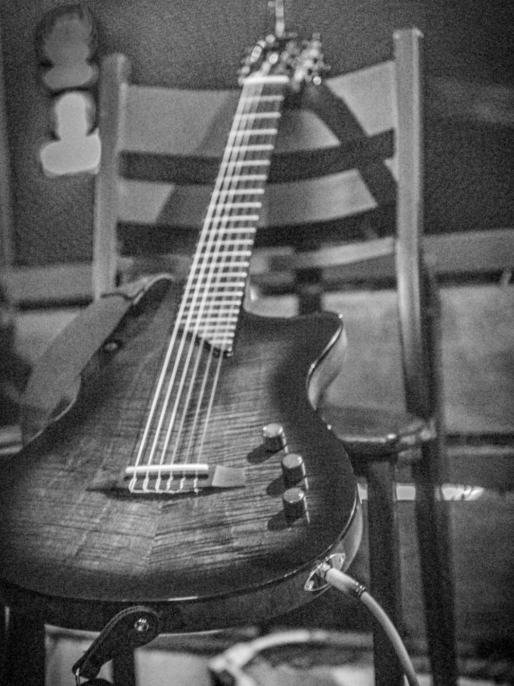 Black and white photograph of an electric guitar body with fretboard in focus.