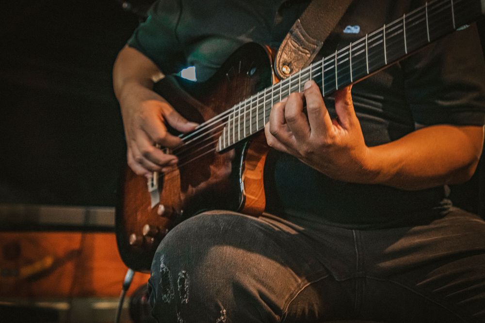 Electric bass guitar player performing on stage in dramatic lighting.