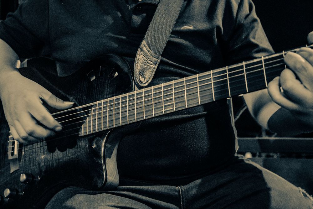 Close-up view of hands playing electric bass guitar strings.