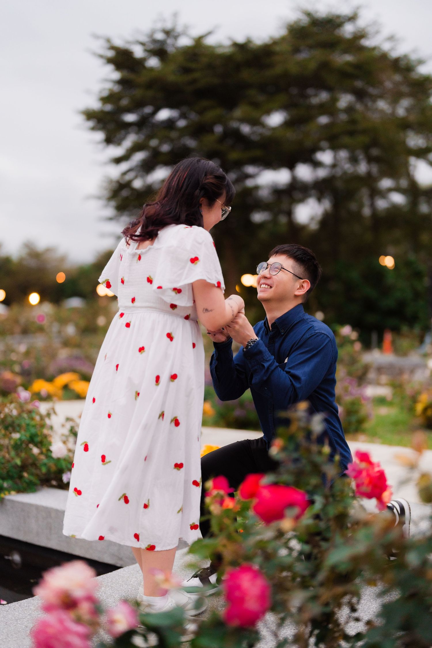 A romantic proposal moment in a blooming garden filled with colorful roses at the Taipei Rose Garden.