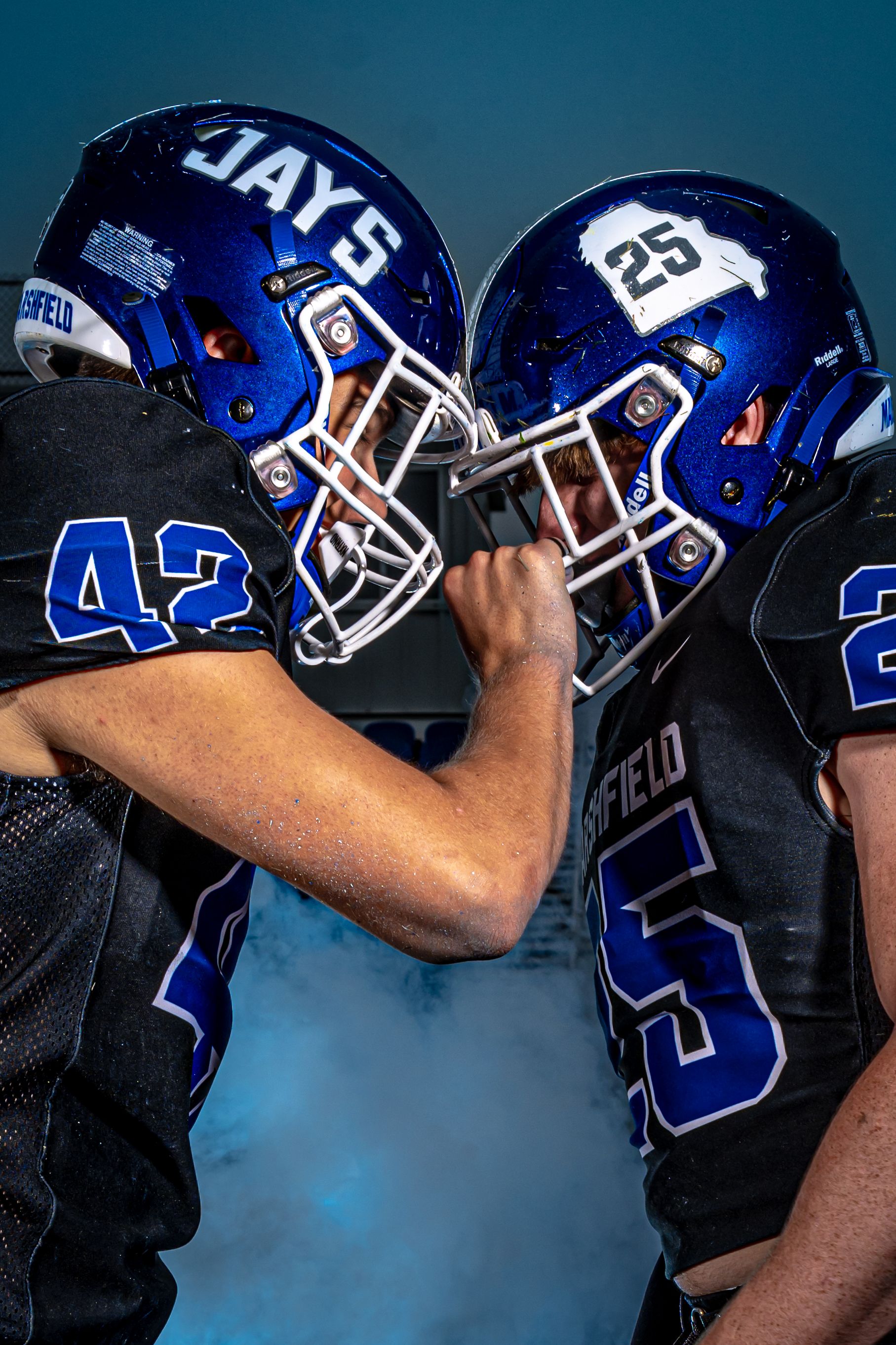 Two football players in blue jerseys and helmets with numbers 42 and 25 faceoff in dramatic pose.