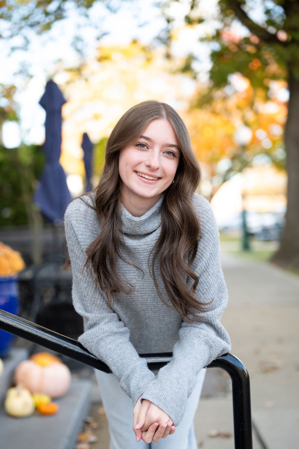 Casual autumn portrait on bench with fall foliage in background.