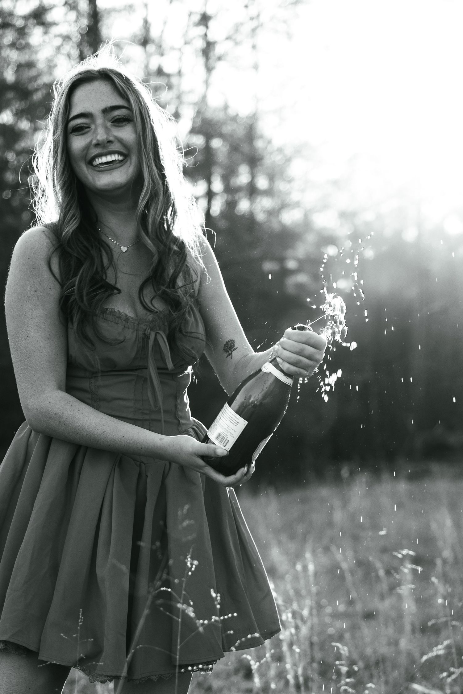 A joyful celebration moment with a champagne bottle spraying in a sunlit field.