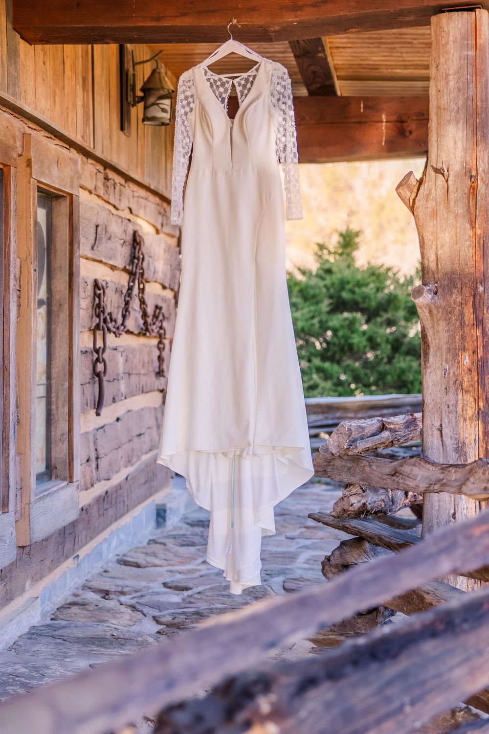 White wedding dresses hanging in a rustic wooden porch setting with natural lighting.