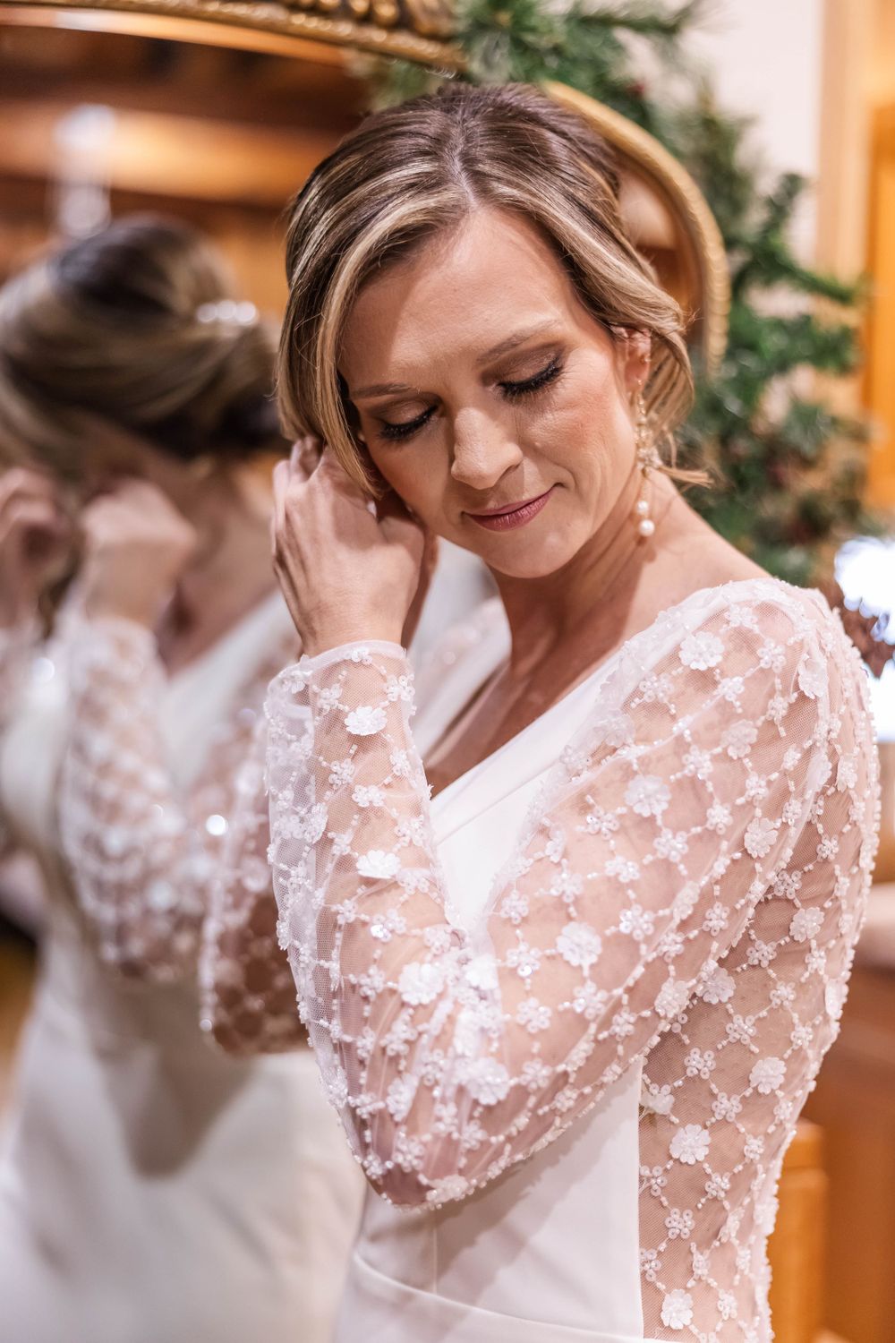 Detail shot of delicate lace sleeves and elegant bridal styling in warm indoor lighting.