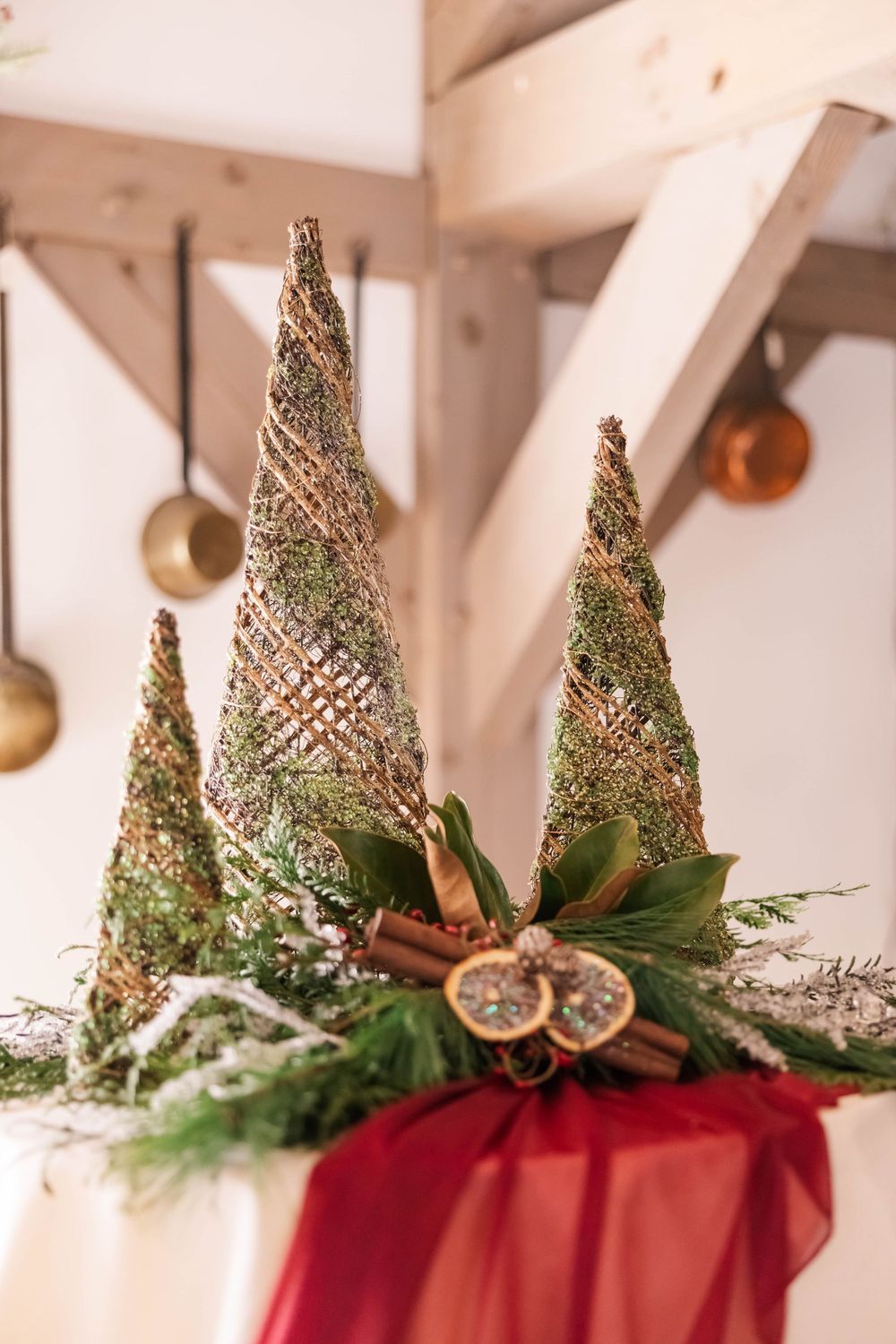 Decorative gold-trimmed Christmas trees with natural greenery and dried orange slice accents.