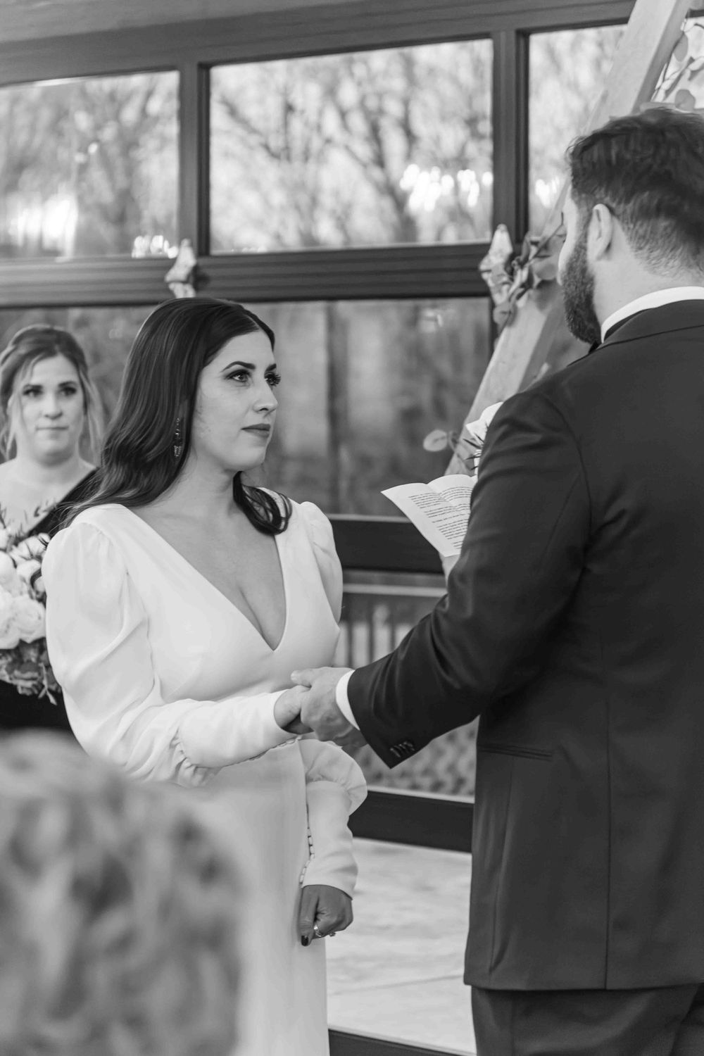 A couple exchanges vows during an intimate wedding ceremony in black and white photography.