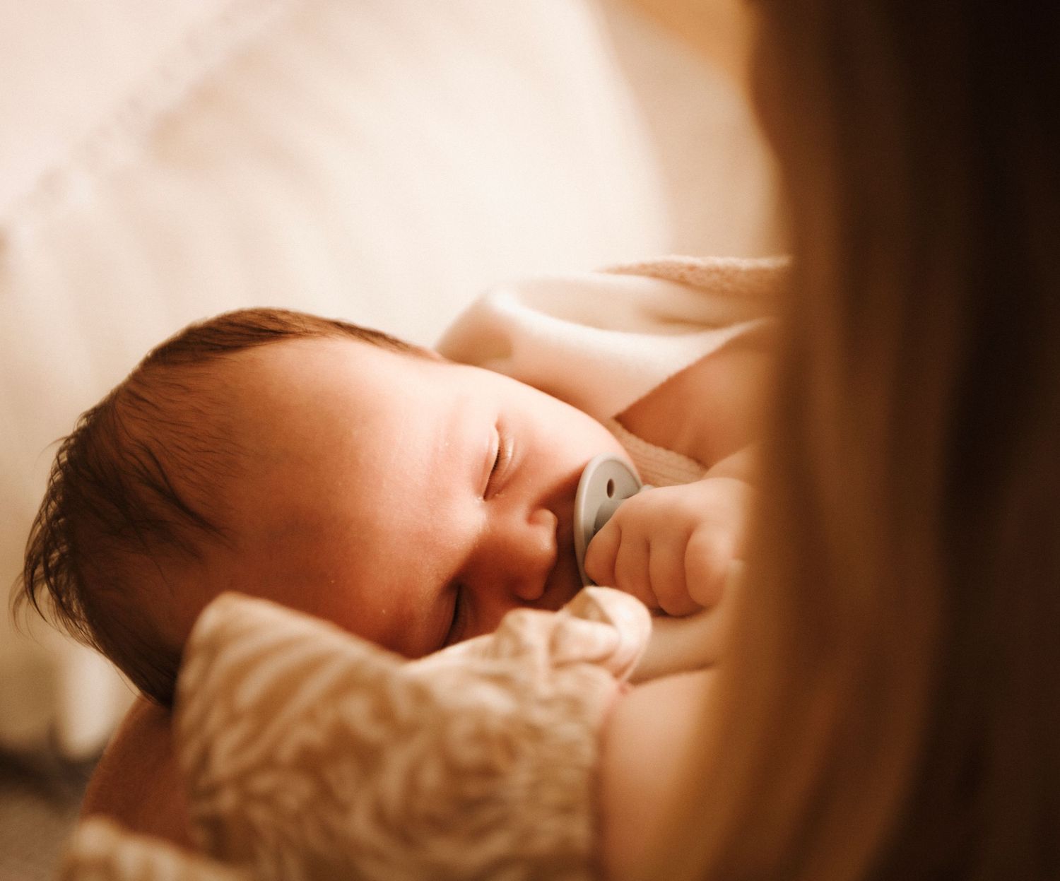 A close-up collage of a sleeping baby's features shown from different angles in warm sepia tones.