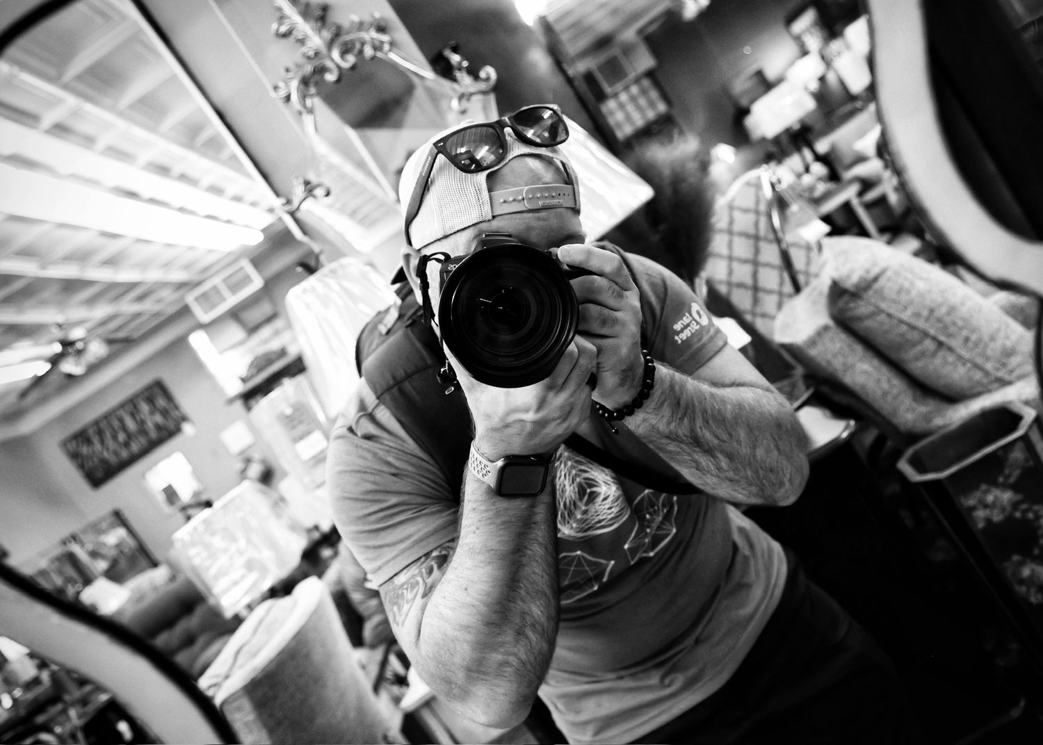 Black and white photo of a photographer holding a camera up to their face.