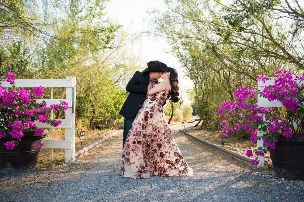 Couple shares romantic moment on path lined with vibrant pink bougainvillea flowers.