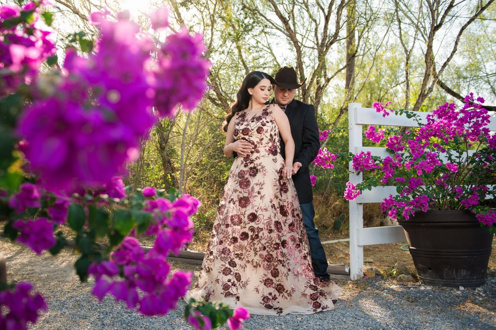 Romantic outdoor portrait with purple flowers framing couple in foreground.
