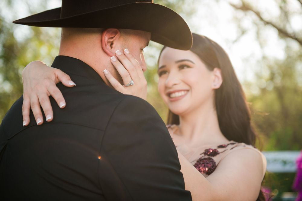 Close-up shot of an intimate embrace with one wearing a cowboy hat and black attire.