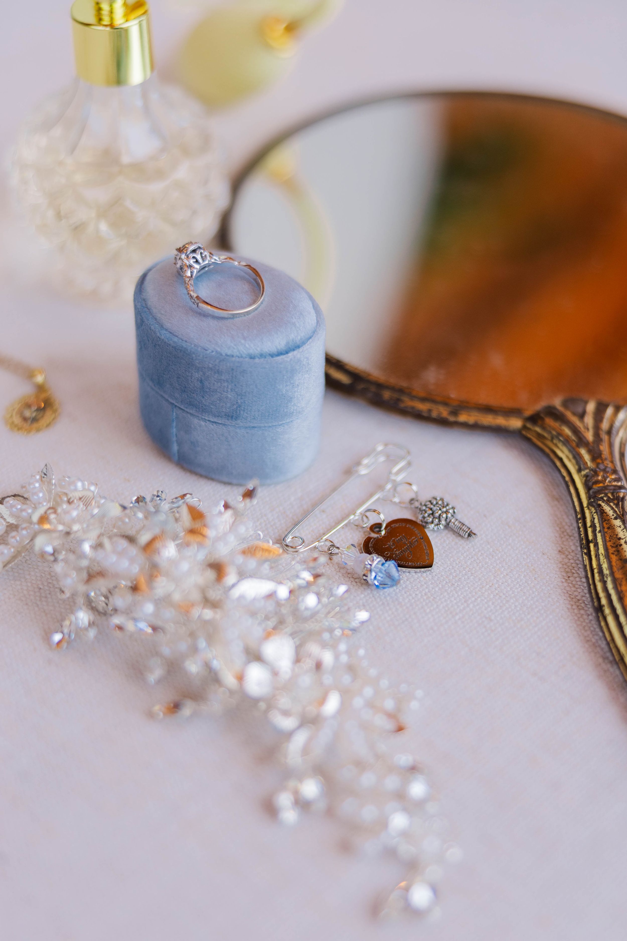 Wedding detail shot of delicate pearl jewelry and a light blue ring box.