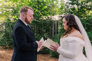 A couple exchanging vows during an outdoor wedding ceremony surrounded by trees and natural light.