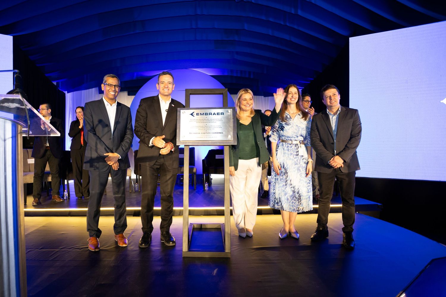 Group of five professionals posing with a Goodyear commemorative plaque at a formal corporate awards ceremony.
