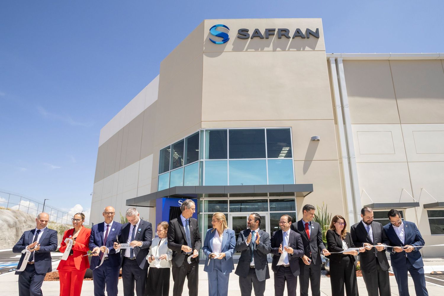 Safran executives celebrate a ribbon-cutting ceremony at a newly opened modern industrial facility building.