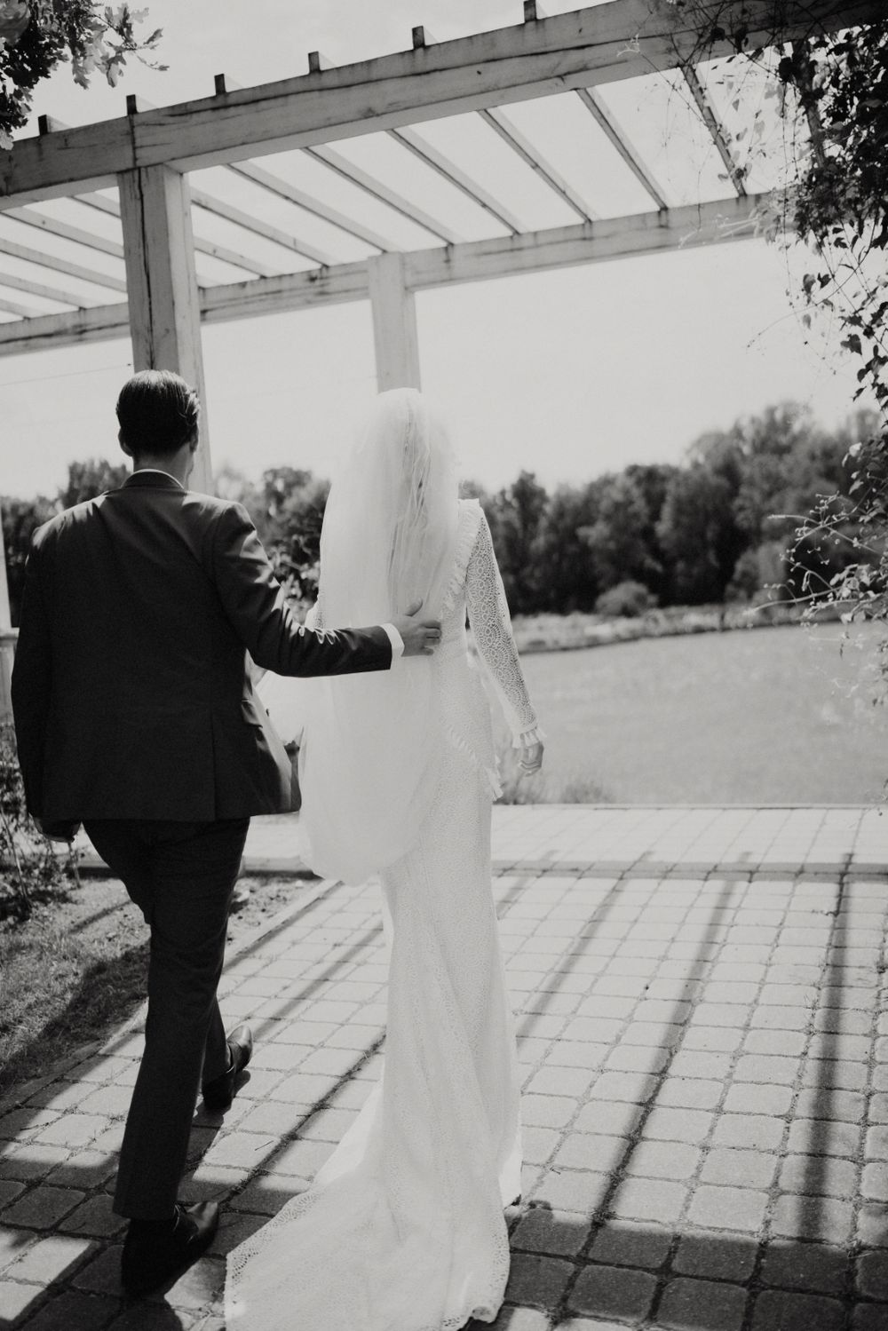 Black and white silhouette of couple under pergola during wedding photoshoot.