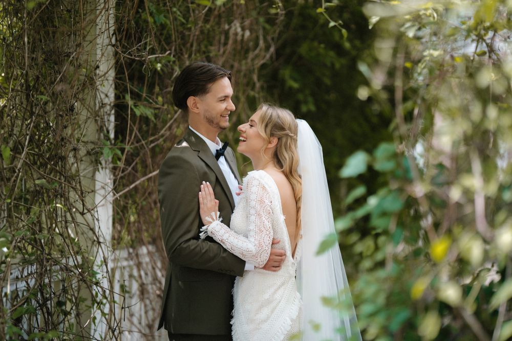 Wedding couple embracing in a garden setting surrounded by greenery.