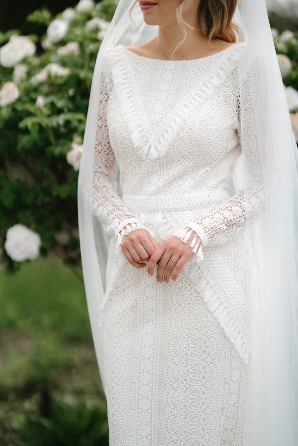 Detailed view of an elegant long-sleeved lace wedding gown with intricate patterns.
