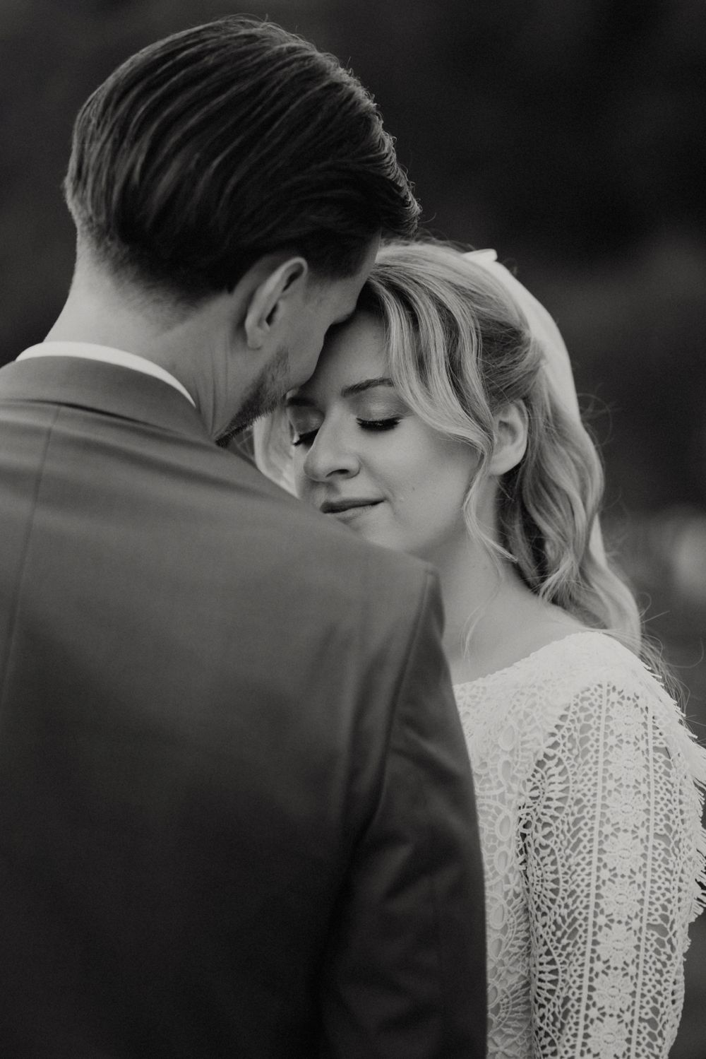 Intimate black and white portrait of newlyweds sharing a tender moment.