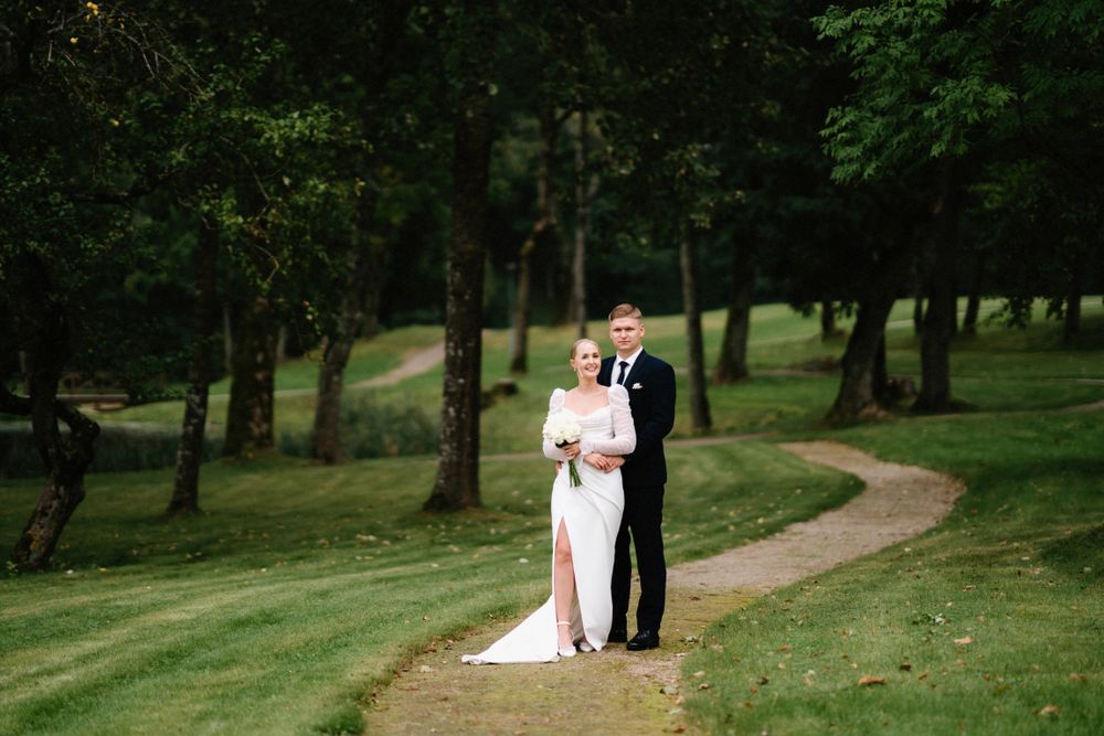 Wedding couple photographed from a distance walking along a winding park path.