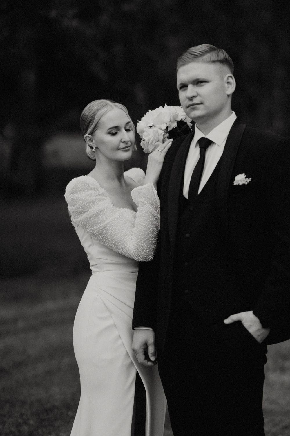 Black and white candid shot of newlyweds sharing a playful moment outdoors.