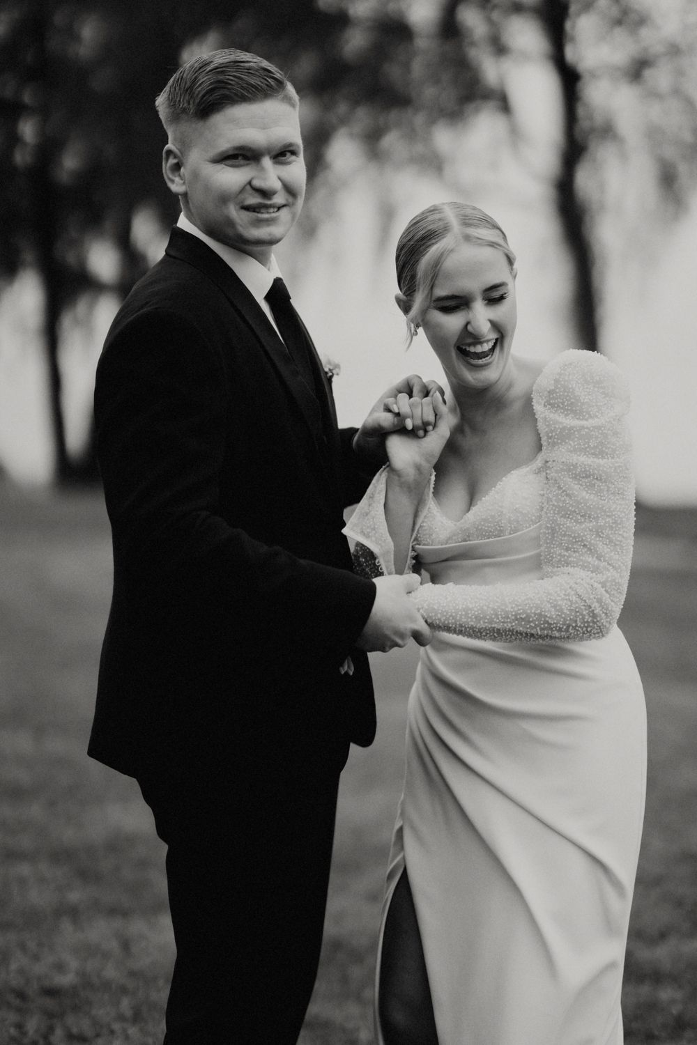 Black and white photo capturing joyful laughter between newlyweds during their wedding portraits.