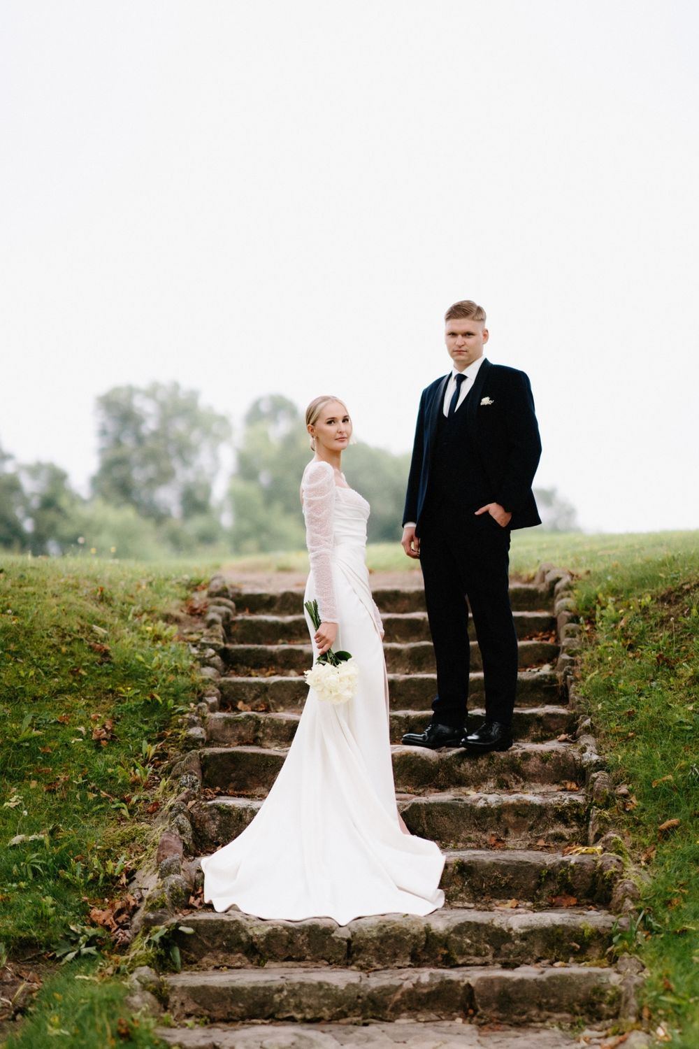 Wedding couple poses on rustic stone steps in a natural outdoor setting.