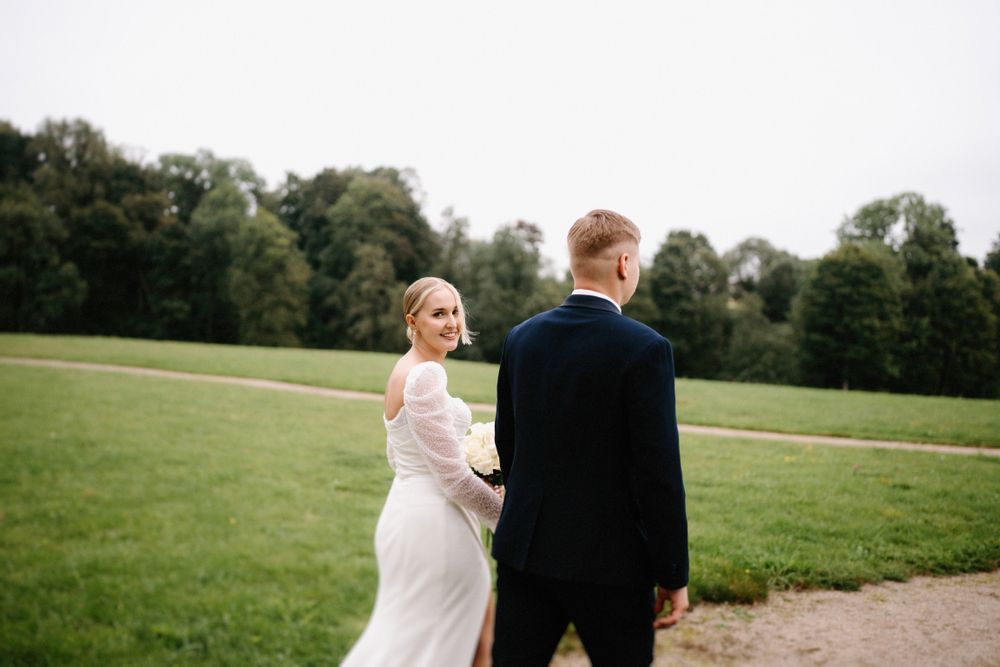 A couple shares a playful moment in a grassy field during their wedding photoshoot.