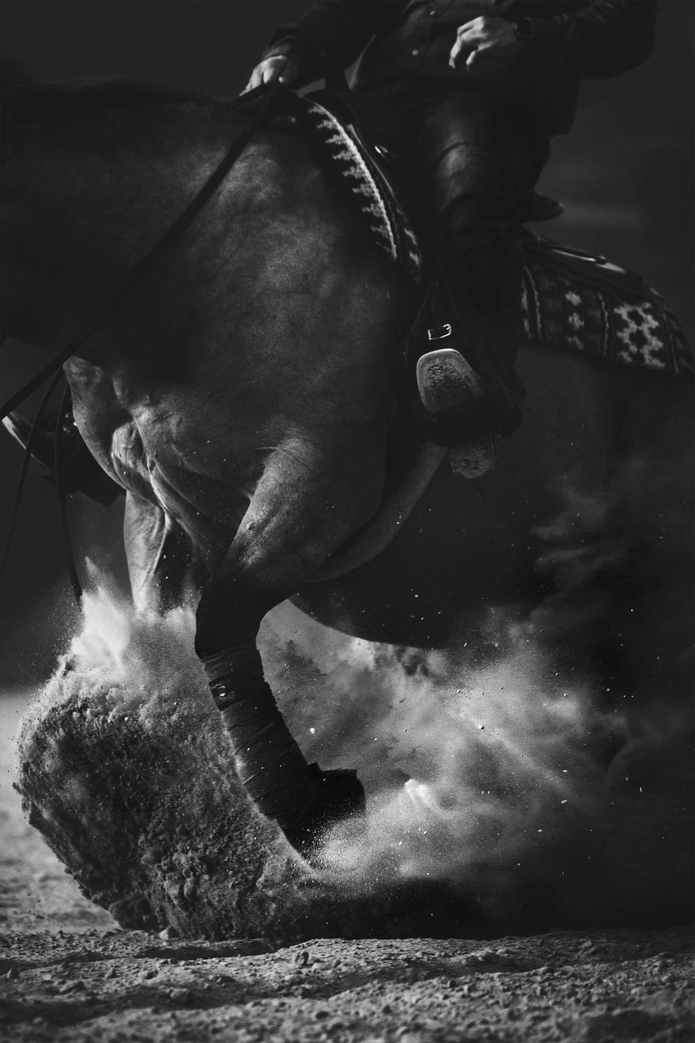 Powerful horse hooves kicking up dust and dirt during sliding stop in black and white photography.