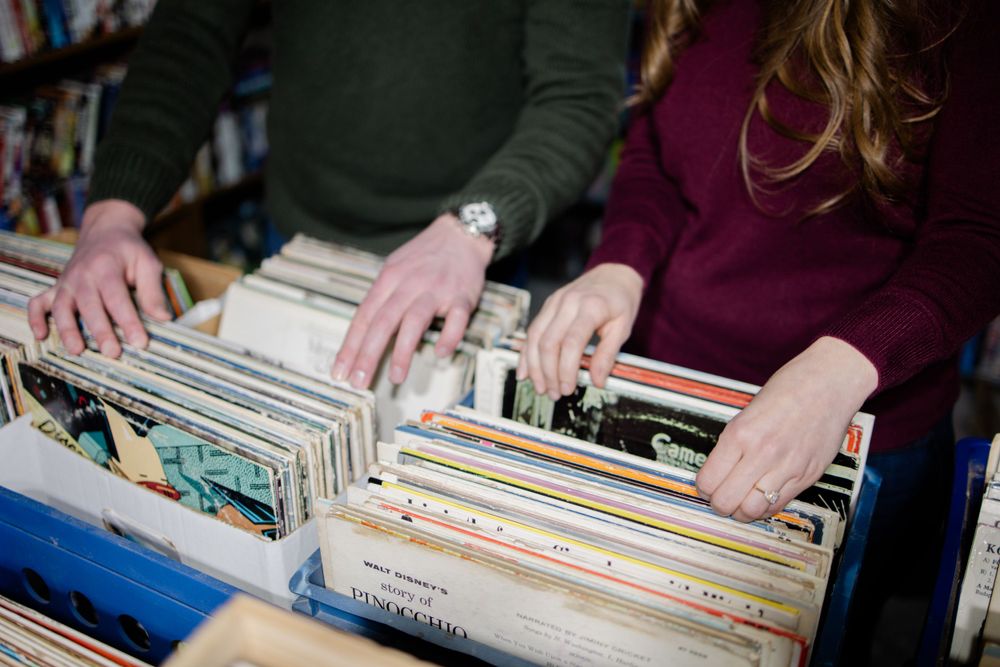 Hands browsing through vinyl records in a record store collection.